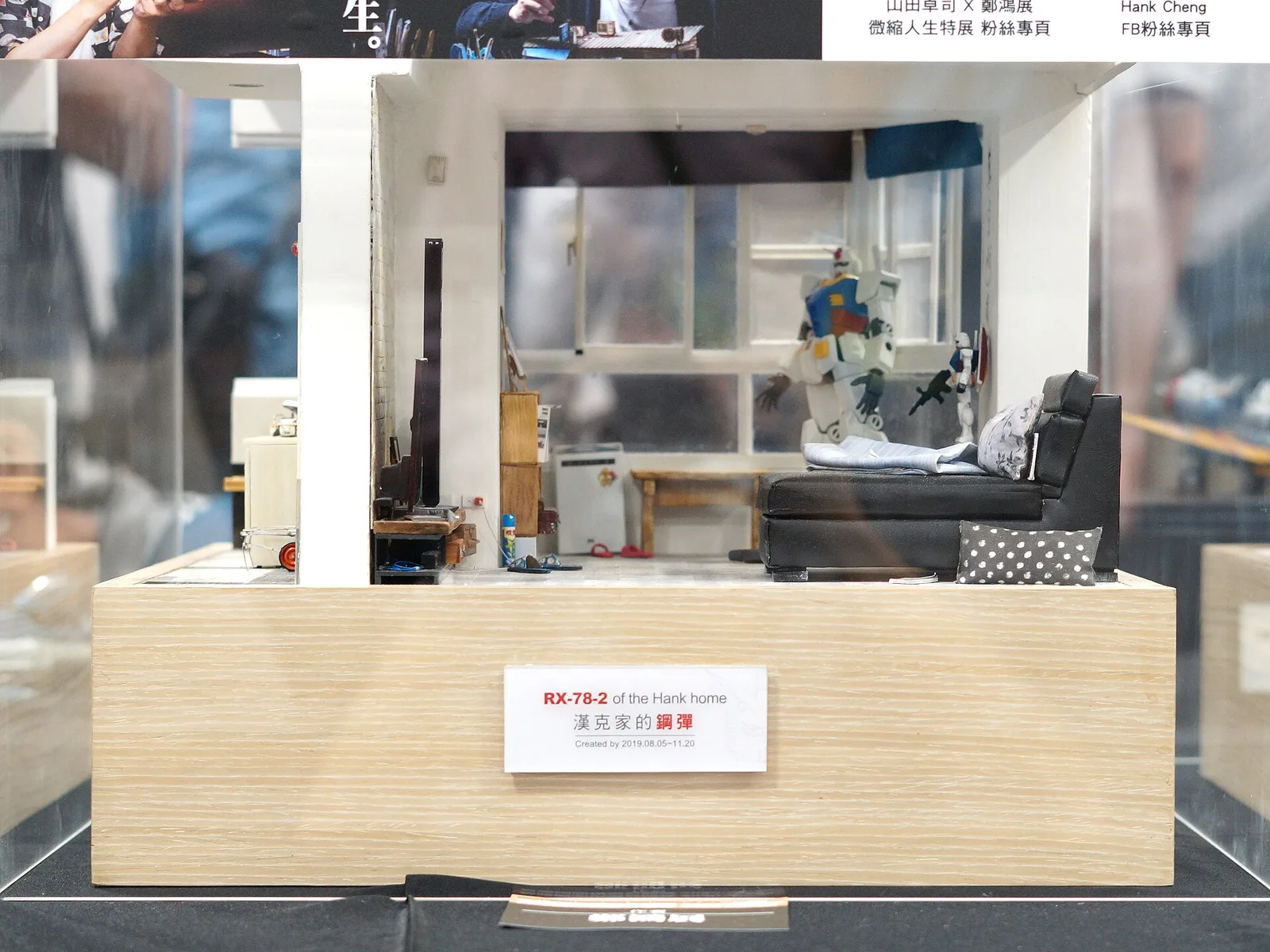 Glass display case with a built RX-78-2 Gundam figure inside a miniature apartment diorama, labeled RX-78-2 of the Hank home