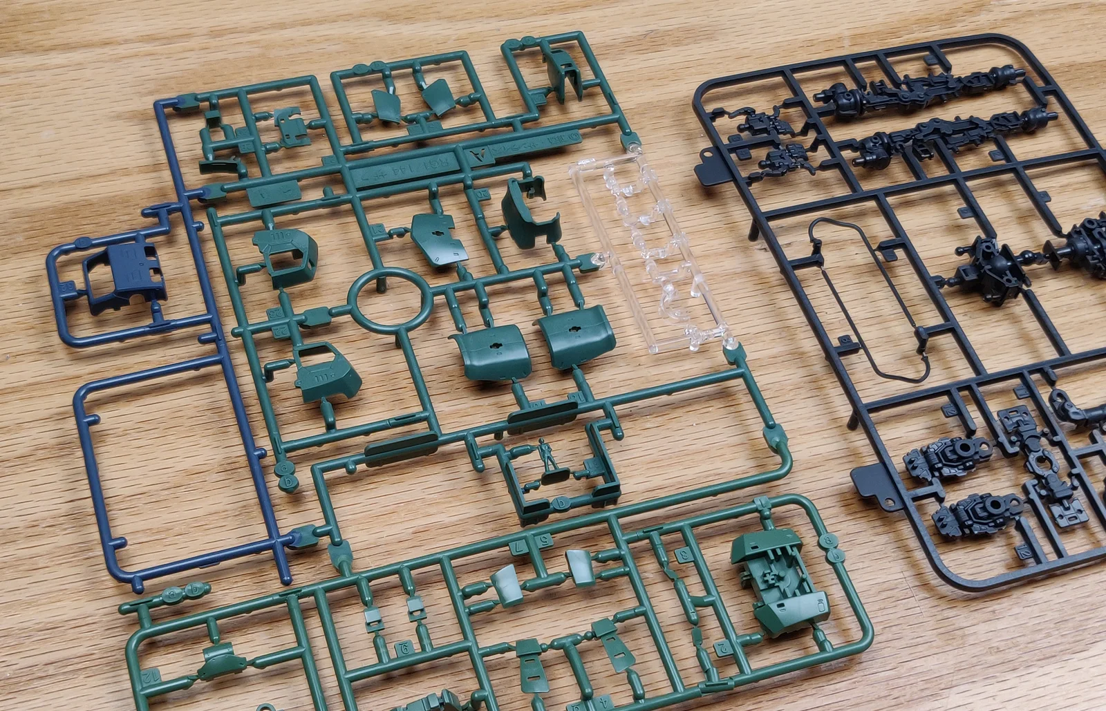 Gunpla runners from a Real Grade Zaku II in green, navy, clear and dark grey plastic, parts still attached